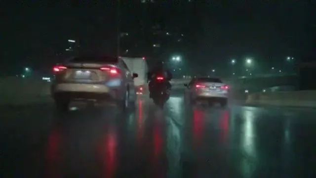 A night motorcycle take on a wet expressway at 360p: soft, grainy and blocky, the rider and the cars smeared, tail lights bleeding into the road